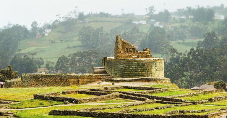 sun temple ruins on a hill with mountains in the background