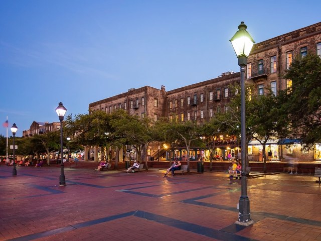 lamps lit on a plaza with historic buildings in Savannah's Waterfront district