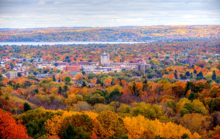 View of Traverse City's downtown landscape in a valley of colorful autumn trees.