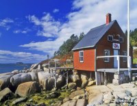 A red lobster house on the rocky coast on a summer day.
