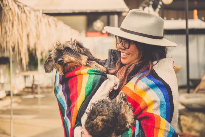 Angie Chua holding dog in a rainbow blanket