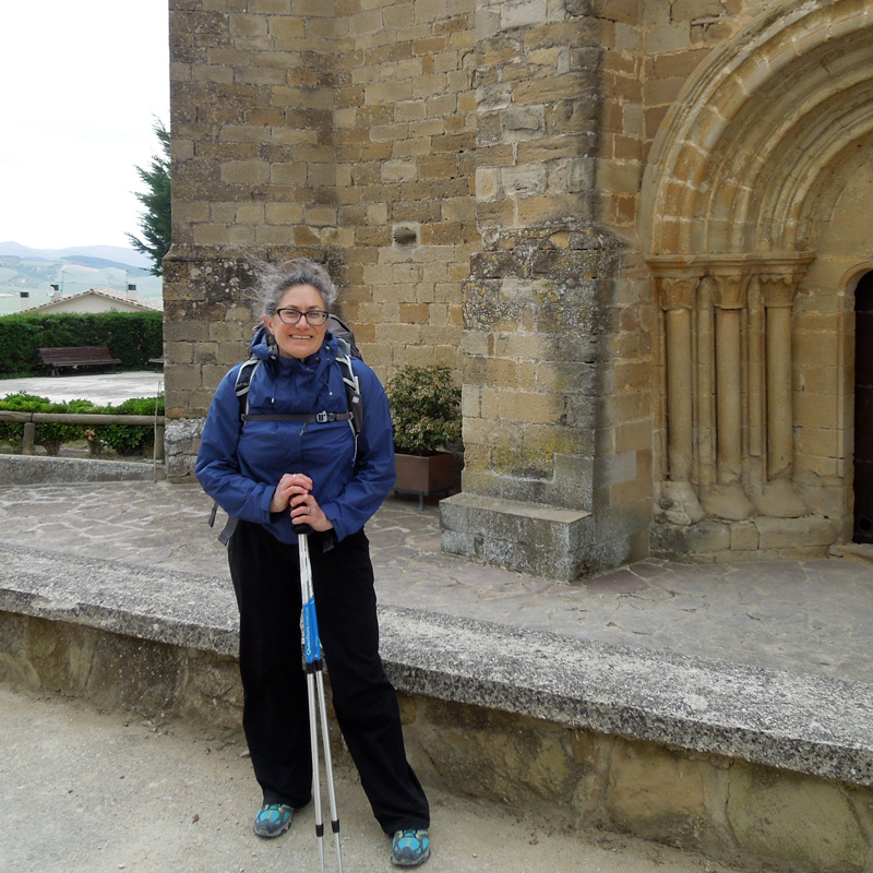woman standing with hiking gear in front of an old buildling