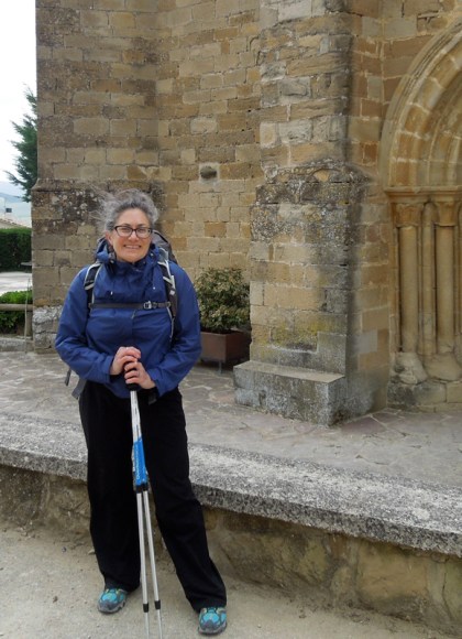 woman standing with hiking gear in front of an old buildling