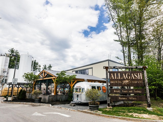 brewery building with a wooden sign and a trailer in front