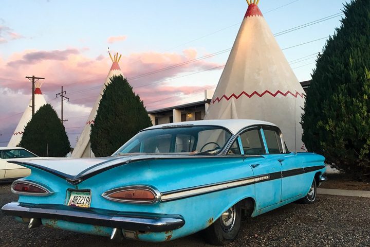 A classic car in front of teepee shaped motel rooms at Holbrook.