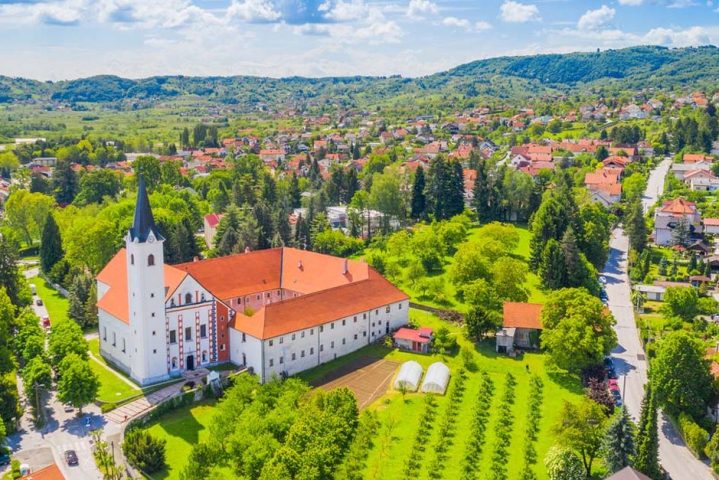 Aerial view of the red-roofed, white buildings, set among the rolling green hills of Samobor, Croatia.