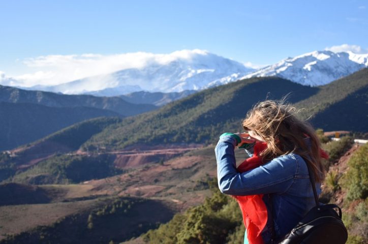 woman looking through binoculars at the mountainous landscape