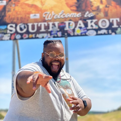 happy black plus size man in front of a South Dakota sign