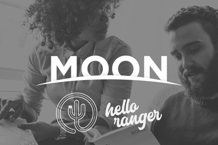 two people looking at a travel guide with logos overlaid that say moon and hello ranger