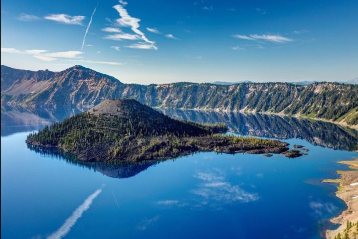 eep blue lake inside a volcano with a stunning reflection of Wizard Island. Crater Lake National Park.